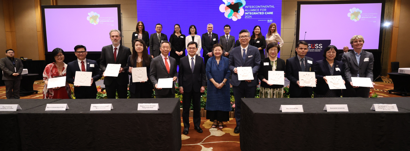 Group of people hold handprint plaques at Intercontinental Alliance for Integrated Care event at SUSS.